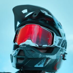 pexels-photo-17462172-17462172 Close-up of a motocross racer wearing a helmet and goggles against a blue sky.